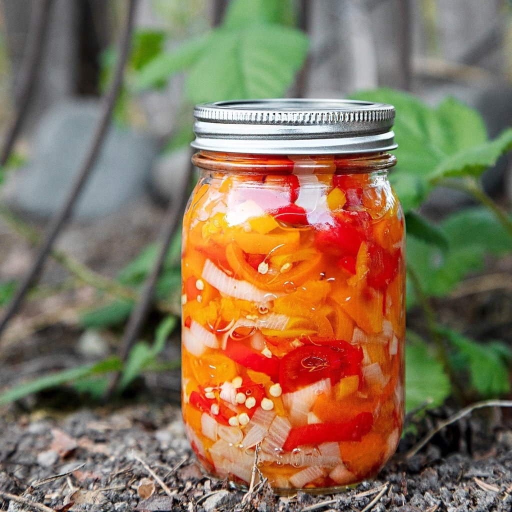 The jar of red and orange sweet peppers, onions, and vinegar