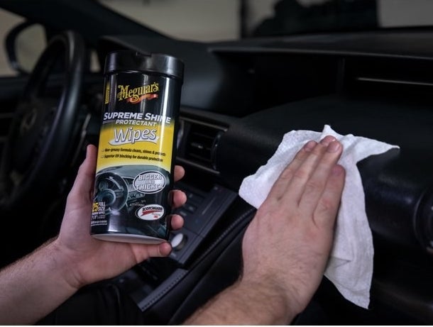The wipes, which are pre-moistened and paper towel-like, being used to polish a dashboard