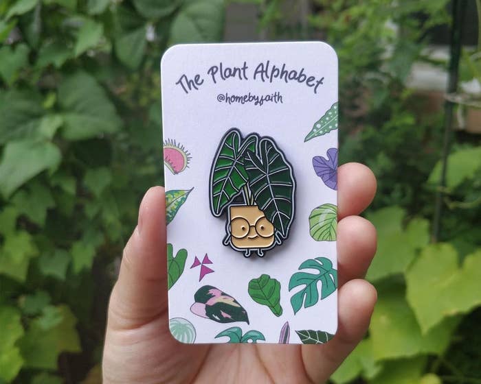 A person holding the plant pin in front of greenery