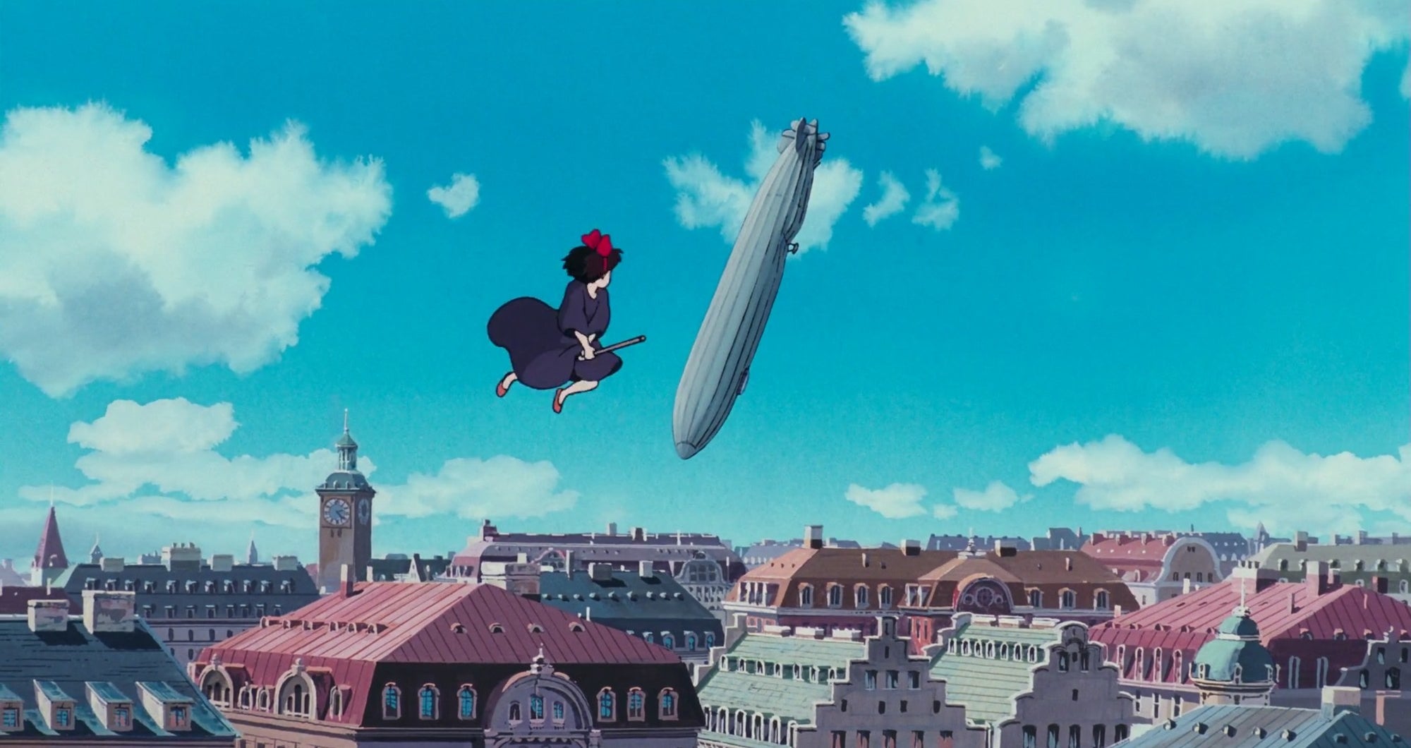 A young girl on a broomstick hovers above a city with a blimp falling from the sky in the background