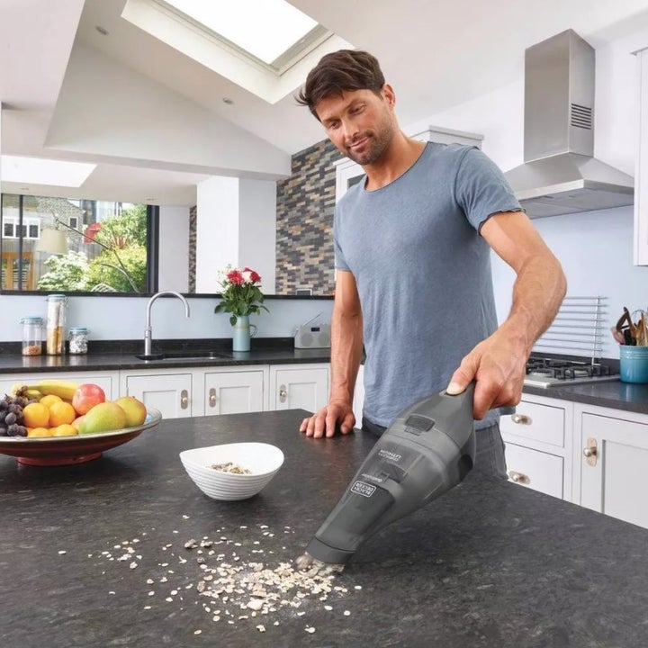 A gray handheld vacuum being used on a countertop