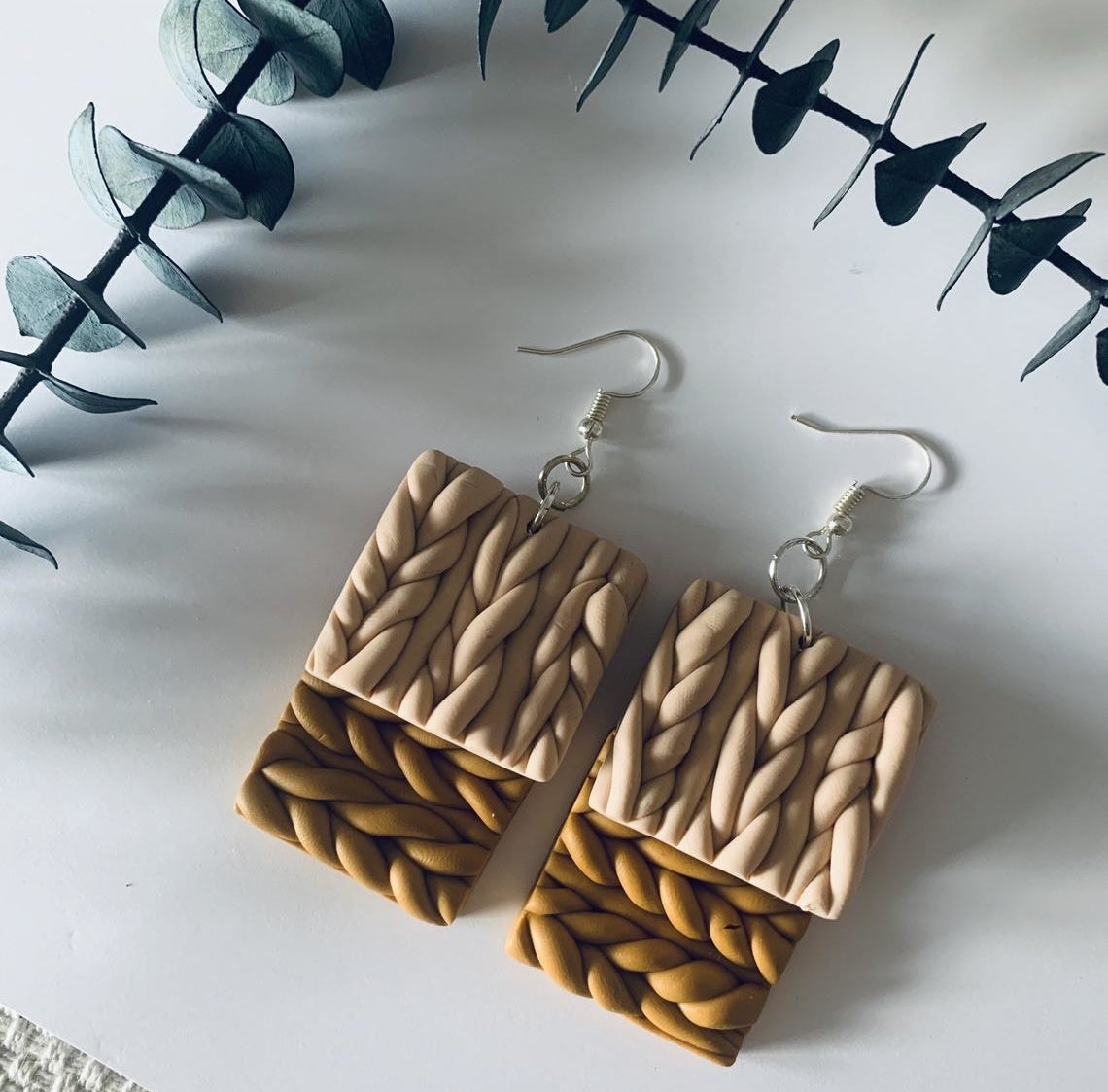 Two pairs of dangly cable knit earrings on top of each other