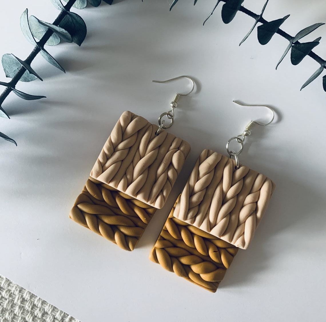 Two pairs of dangly cable knit earrings on top of each other