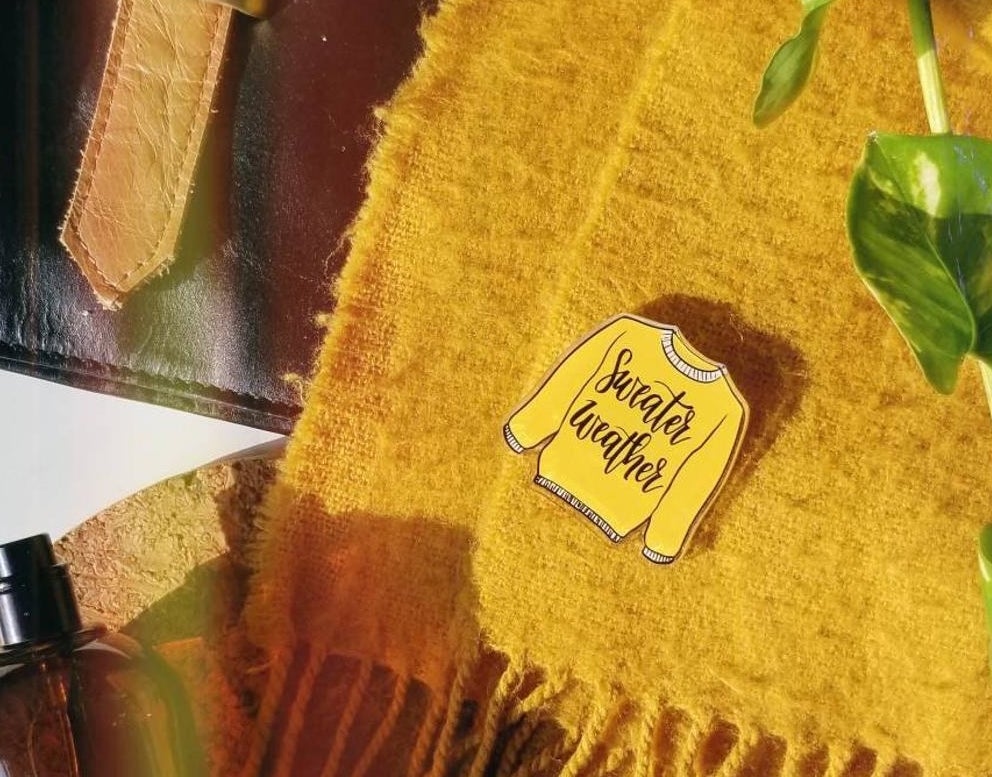 A sweater weather pin on top of a scarf