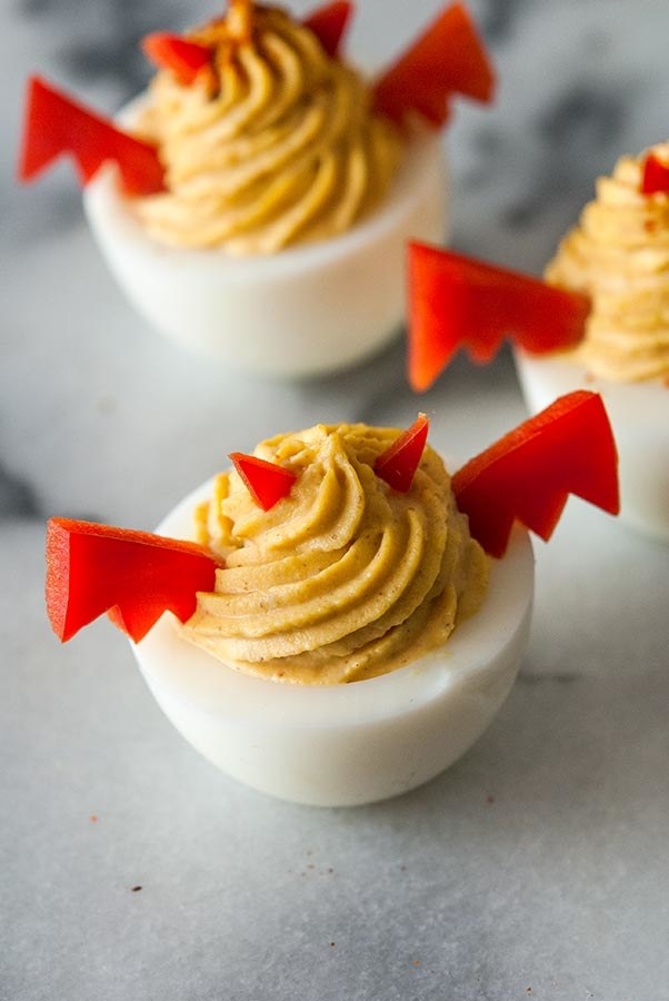 Two Halloween deviled eggs with pepper wings and horns.