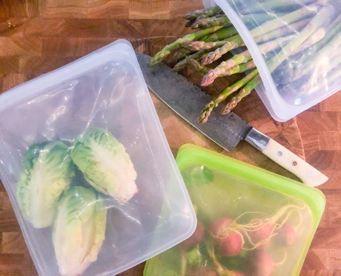 A flatlay of the silicone bags, all containing fresh produce, like radishes, lettuce, and asparagus
