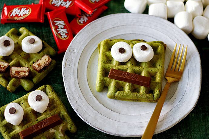 Homemade matcha monster waffles decorated with KitKat bars, marshmallows, and chocolate chips.