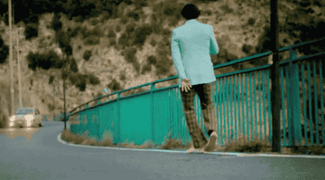 Harry spins around as he dances next to the side of a road