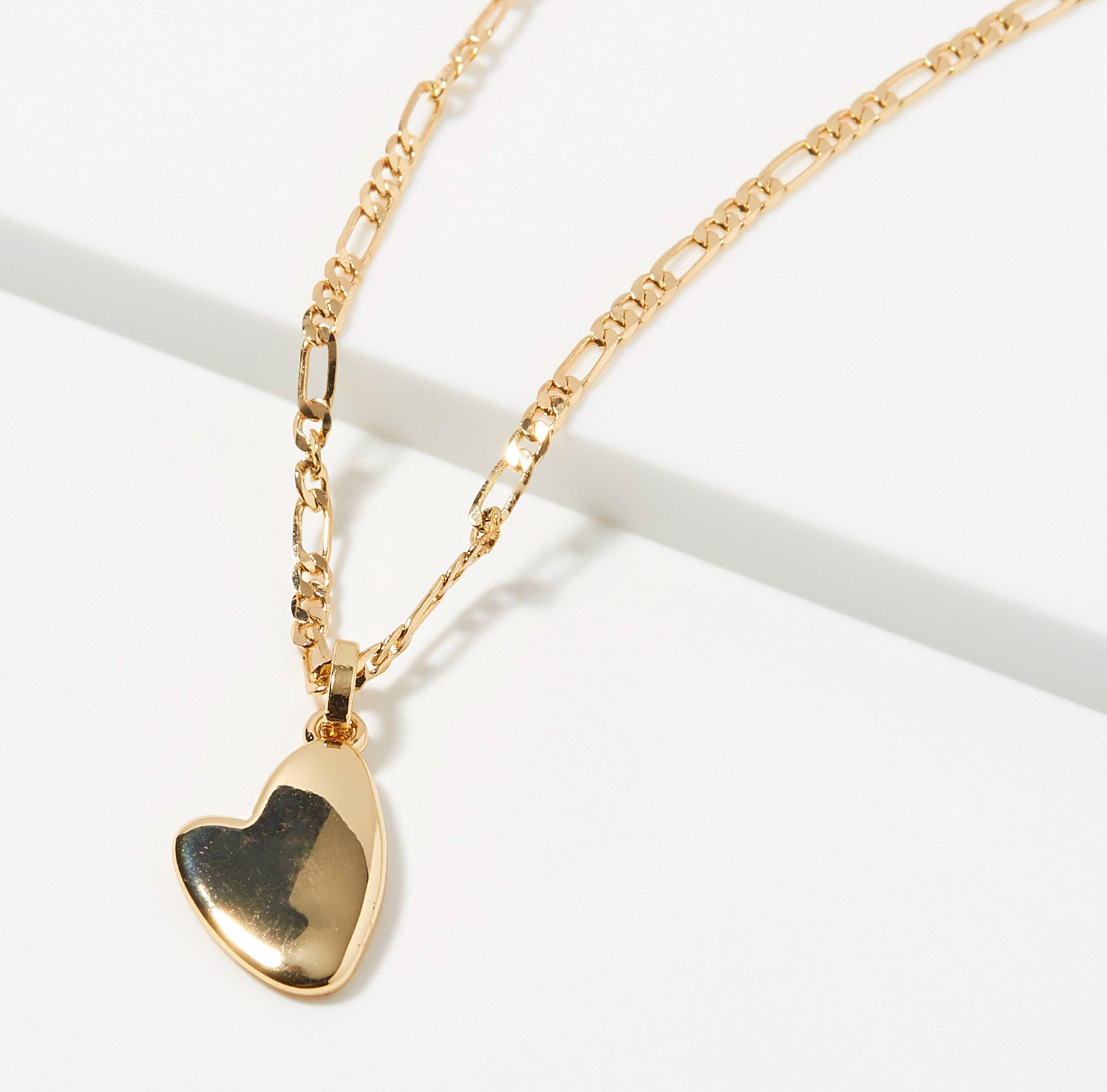 A gold chain necklace with a heart-shaped pendant