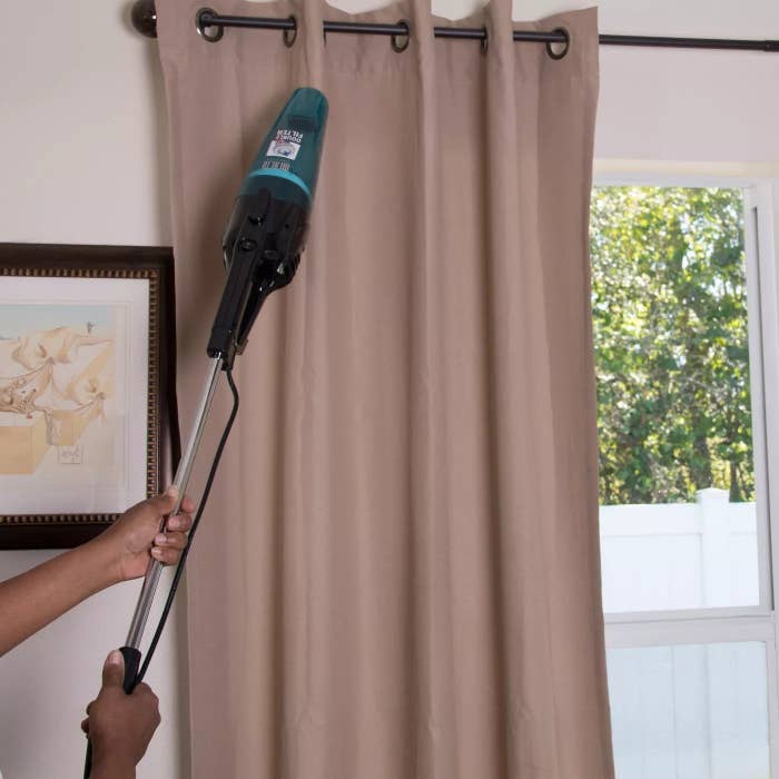 The vacuum extended to clean the top of a curtain