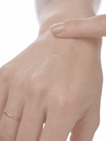a gif of a model applying the shimmery lotion to her hand
