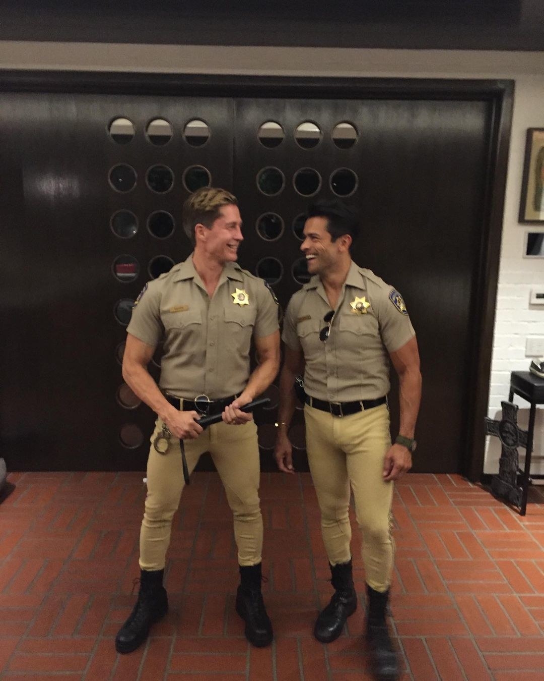 Mark Consuelos posing in an law enforcement costume next to a man wearing a similar outfit