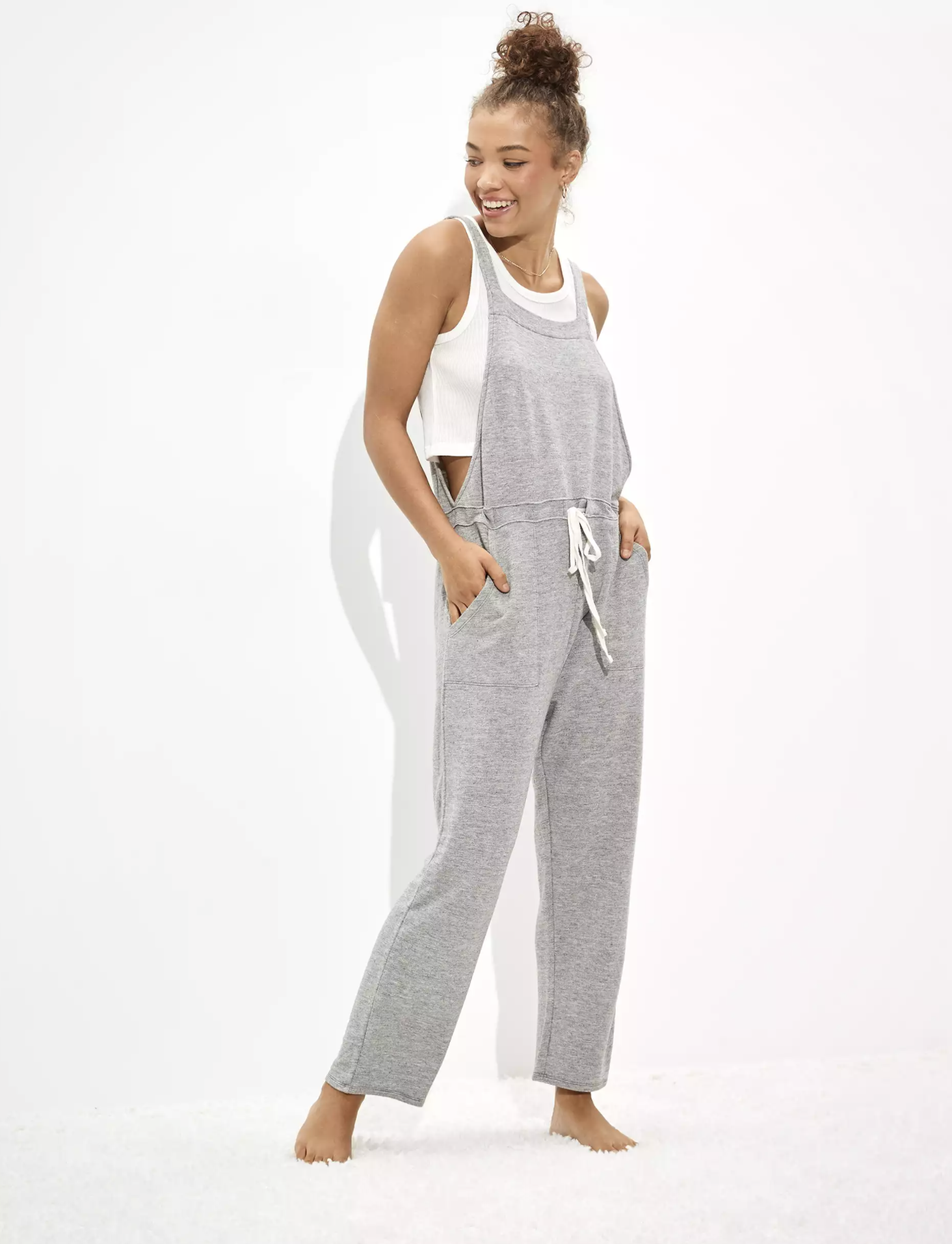 A model wearing the overalls in gray with a white drawstring 