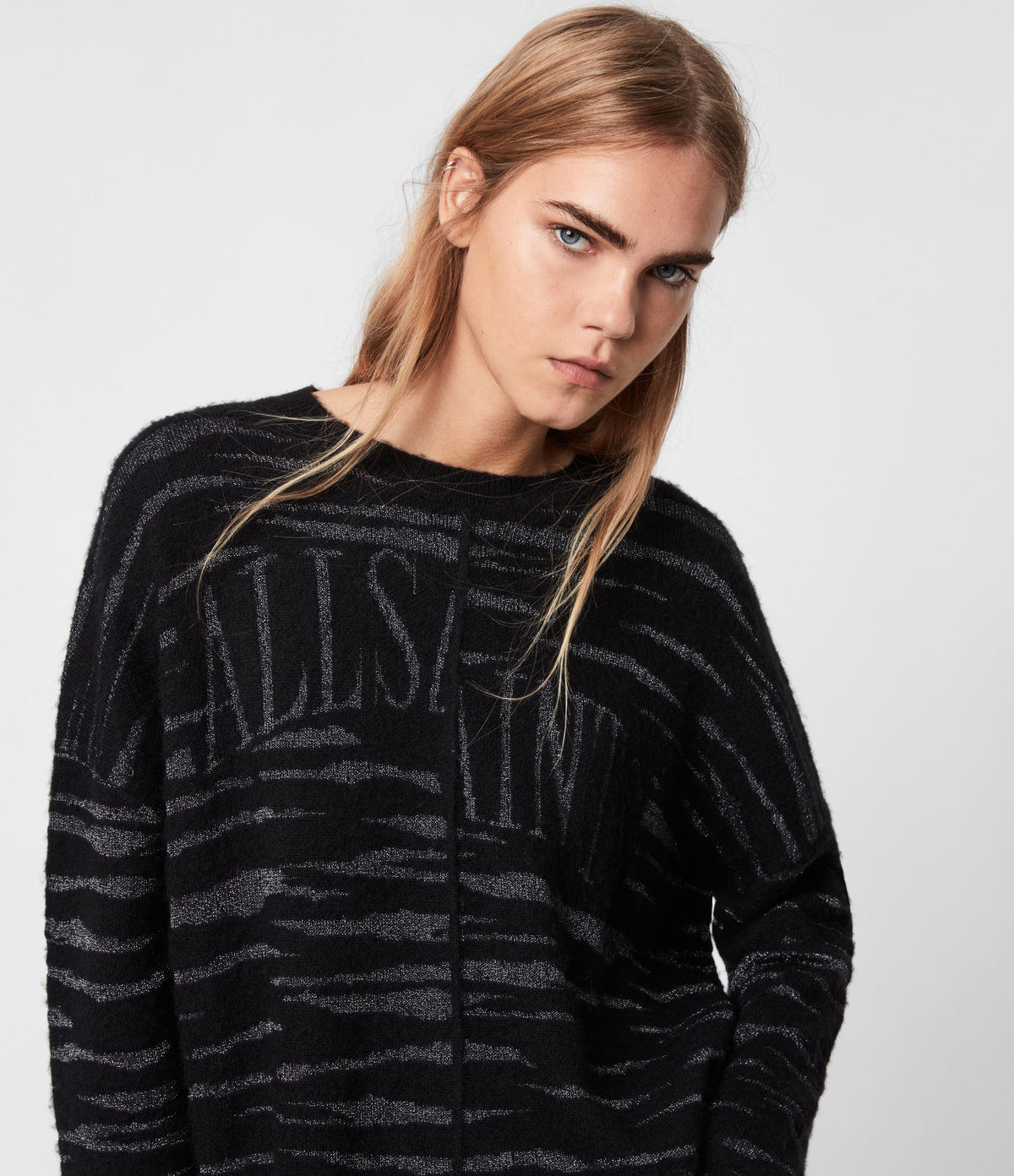a model in a black and grey tiger print sweater with all saints written on the front