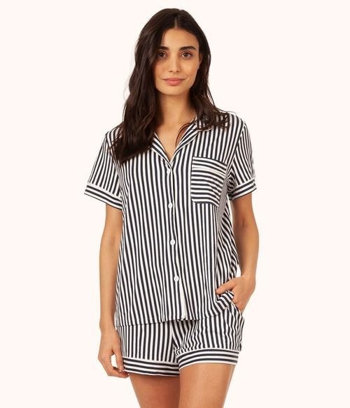A model wearing the black and striped set — shorts ad a buttoned tee with a pocket