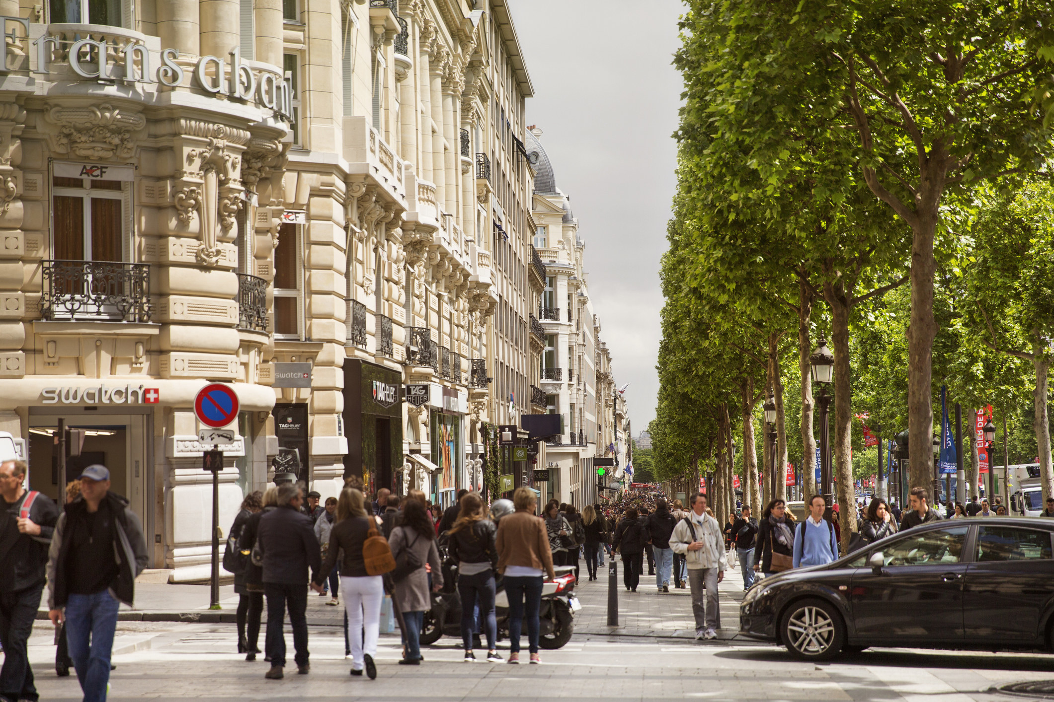 pedestrians walk down the busy Avenue des Champs-Elysees 