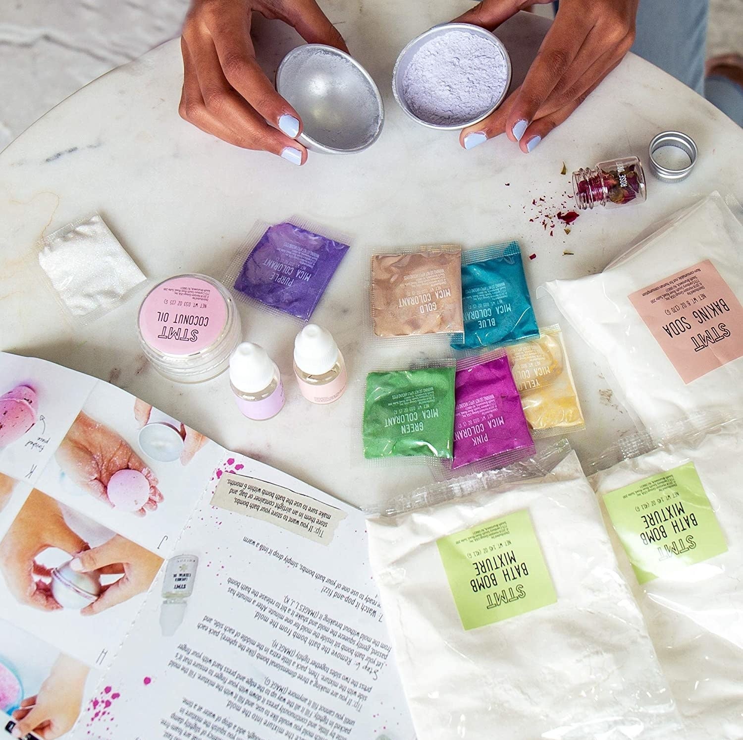 Model using an unboxed bath bomb kit with instruction manual on table