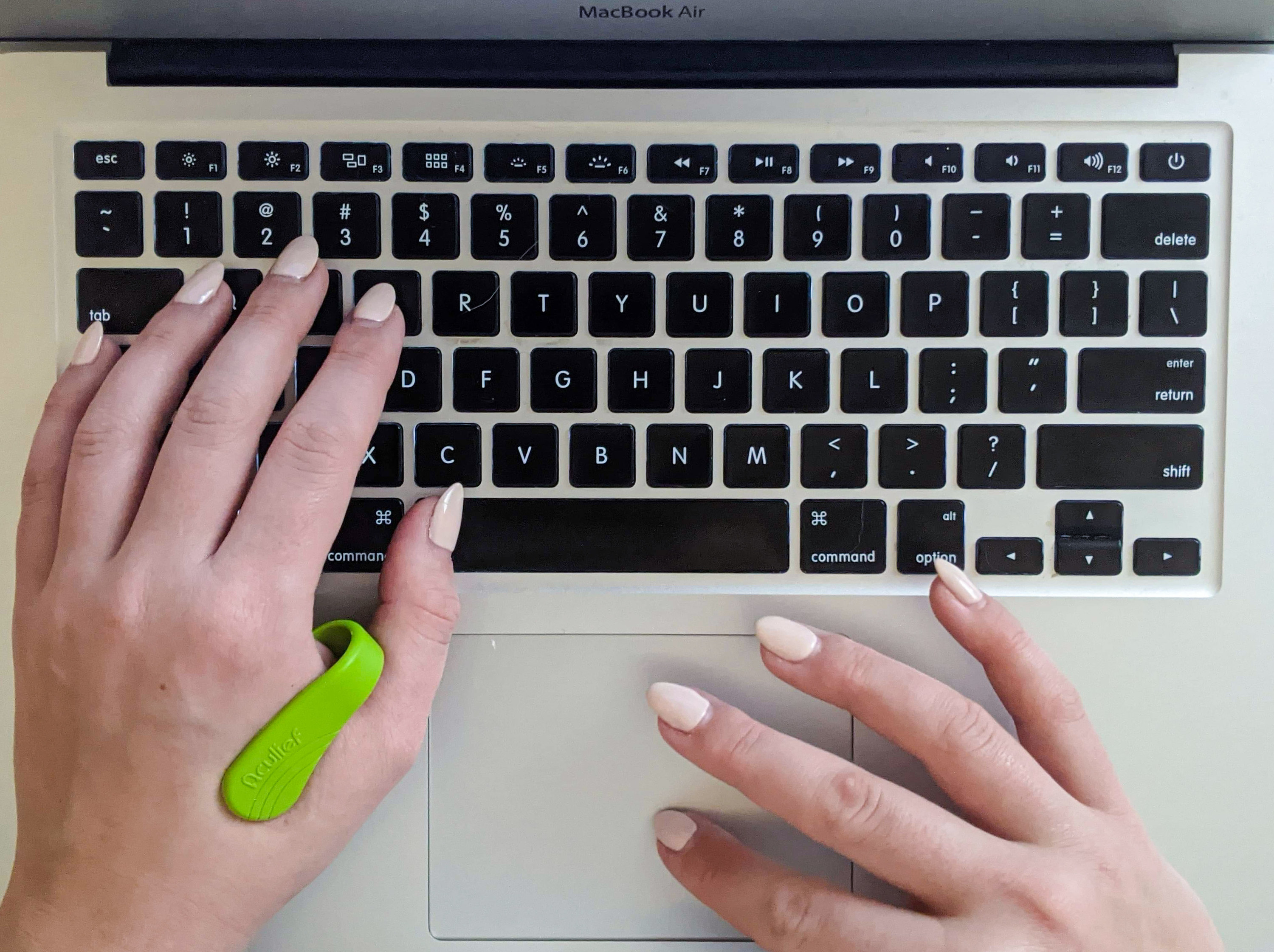 A top down shot of a person typing on their keyboard while wearing the acupressure tool