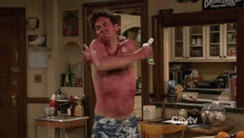 An extremely sunburnt man tries and fails to put a soothing cream on his back