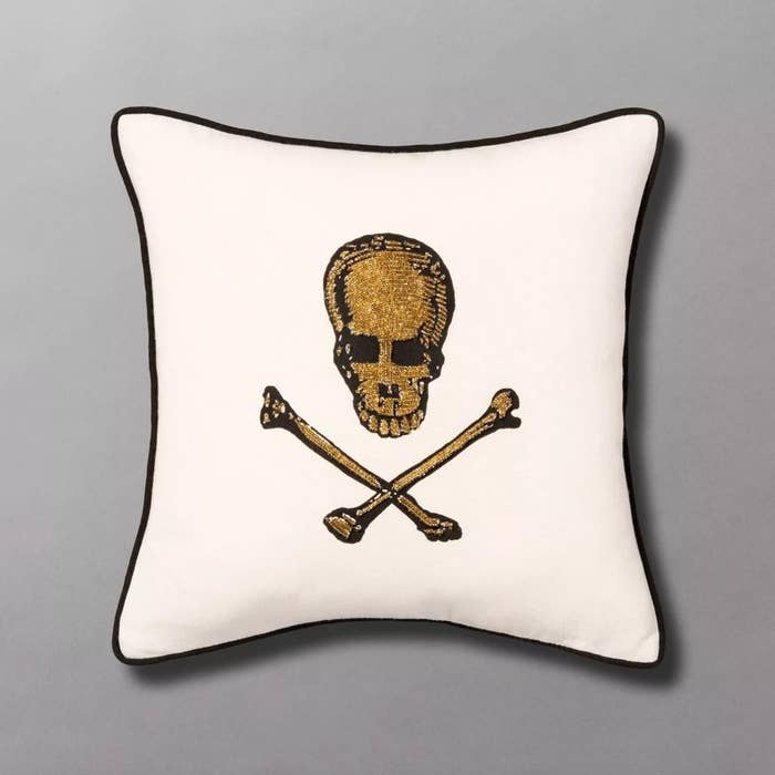 The skull and bones throw pillow in white with gold embroidery