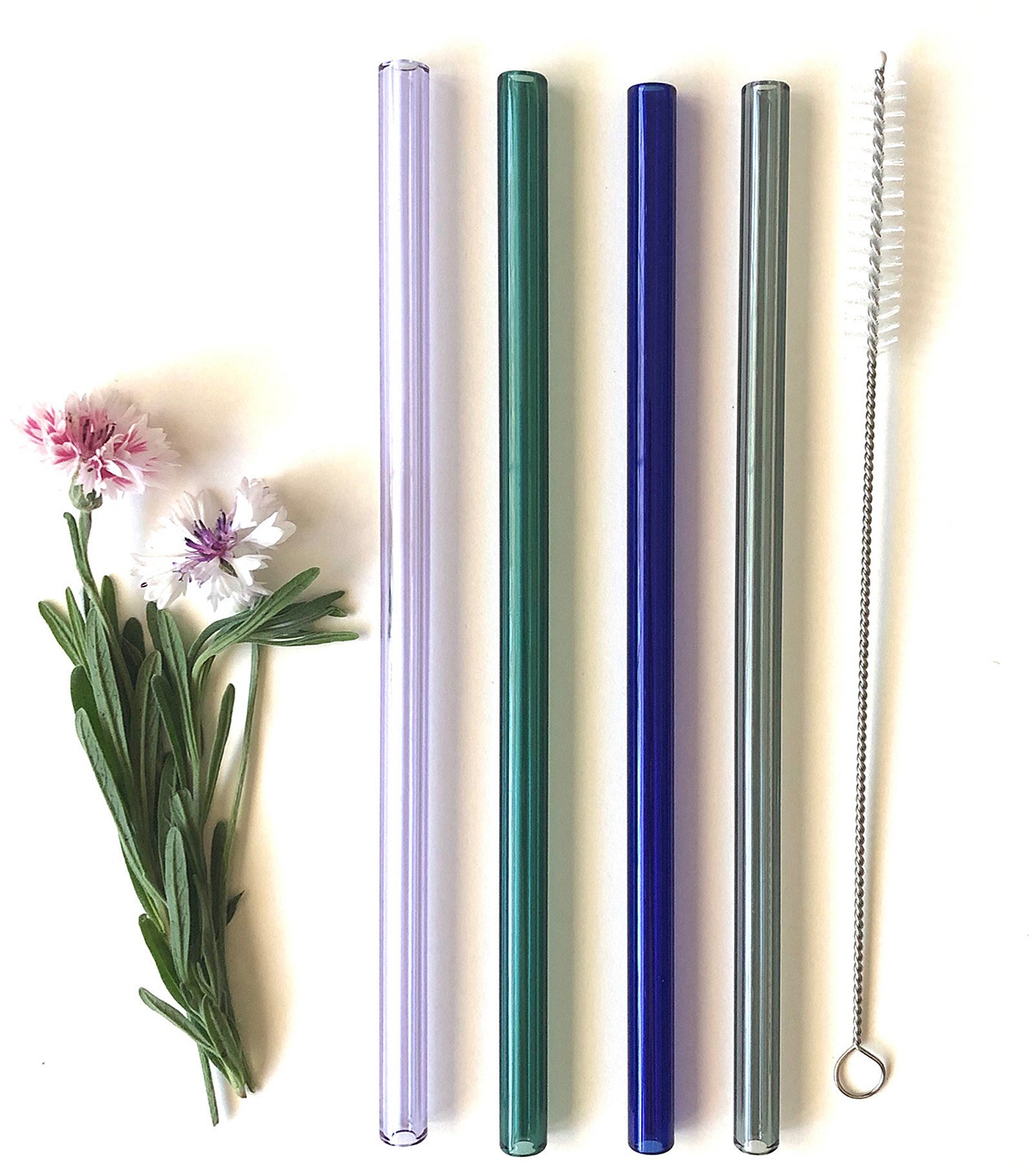 A set of four glass straws and a small cleaning brush on a plain background