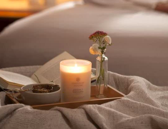 Chesapeake Bay Peace + Tranquility candle lit on a bedside tray with a vase and gray bowl