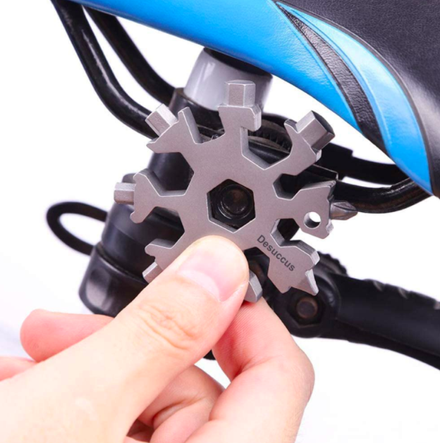 Hand holds silver snowflake-shaped multitool to repair a bike part