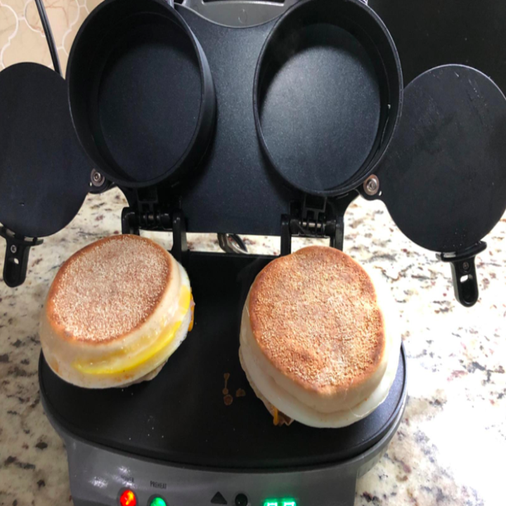 Two breakfast sandwiches being cooked in the dual sandwich maker