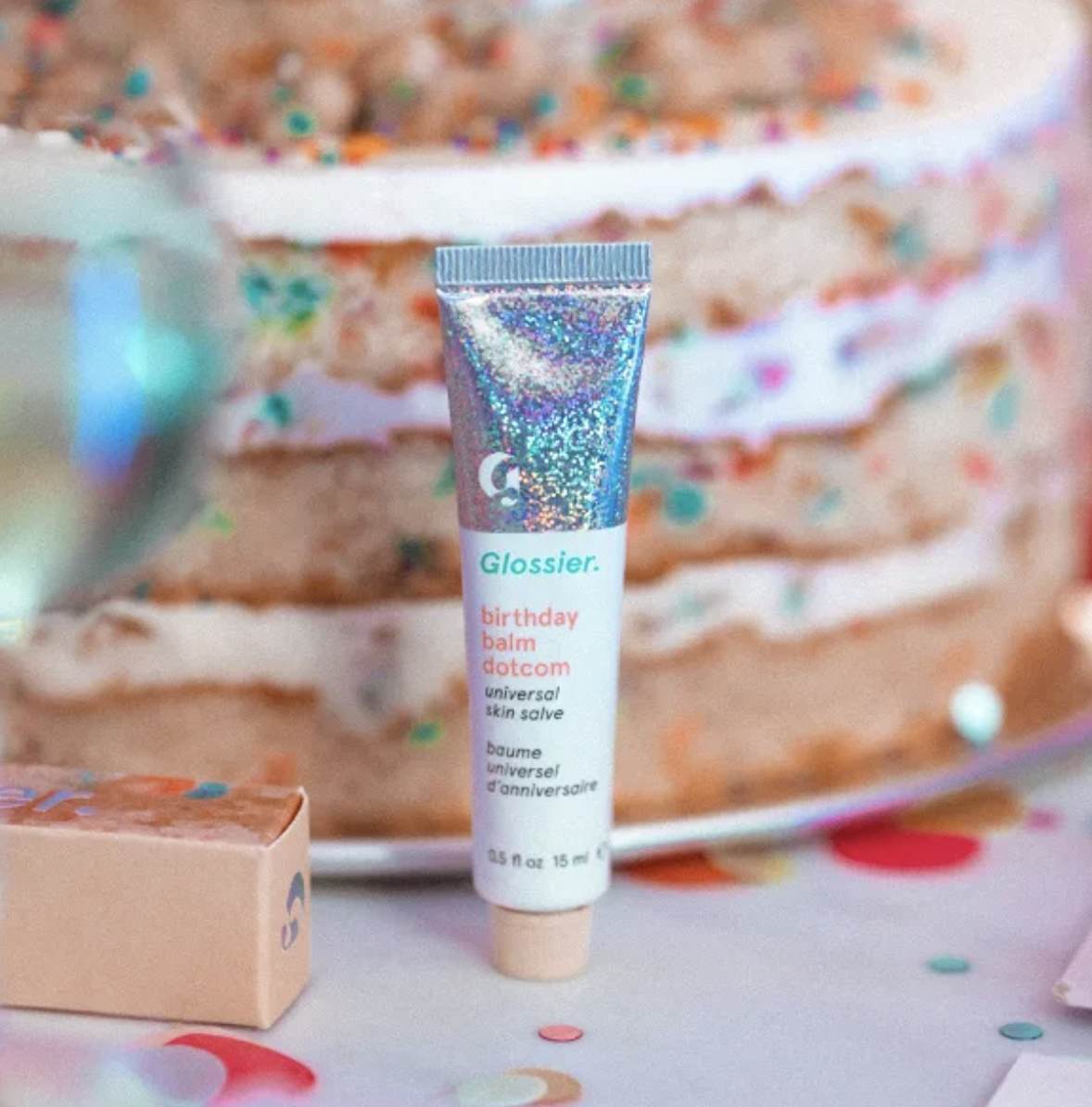 A shimmery tube of lip balm posed in front of a cake 