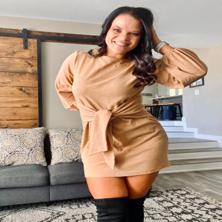 Reviewer wearing long sleeved mini dress in tan with tie wrapped in front