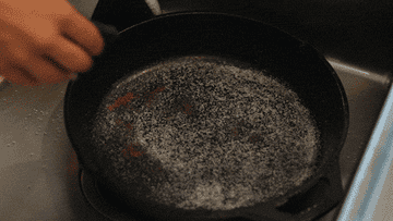 Scrubbing a cast iron pan with salt.