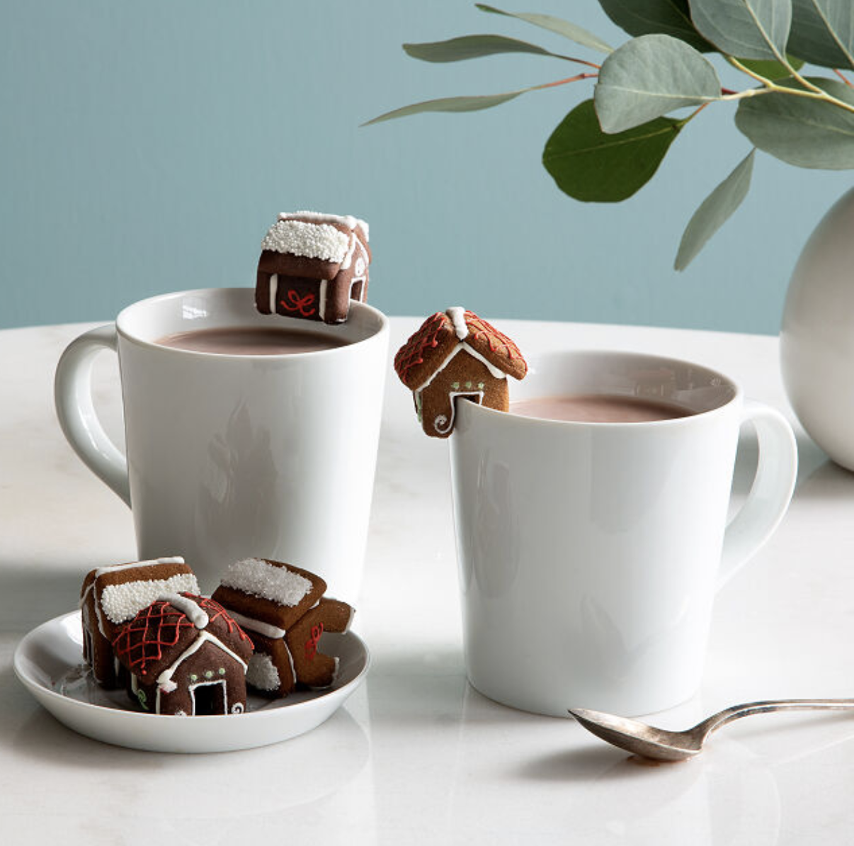 mugs that have little gingerbread houses perched on the lip of them 