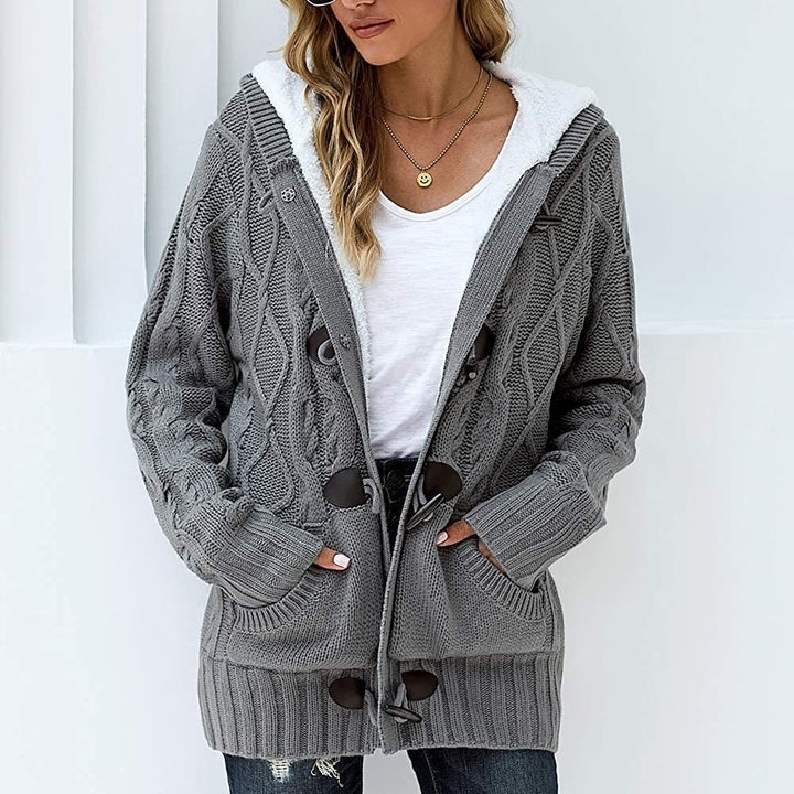 Model wearing sweater in gray with hands in front pockets