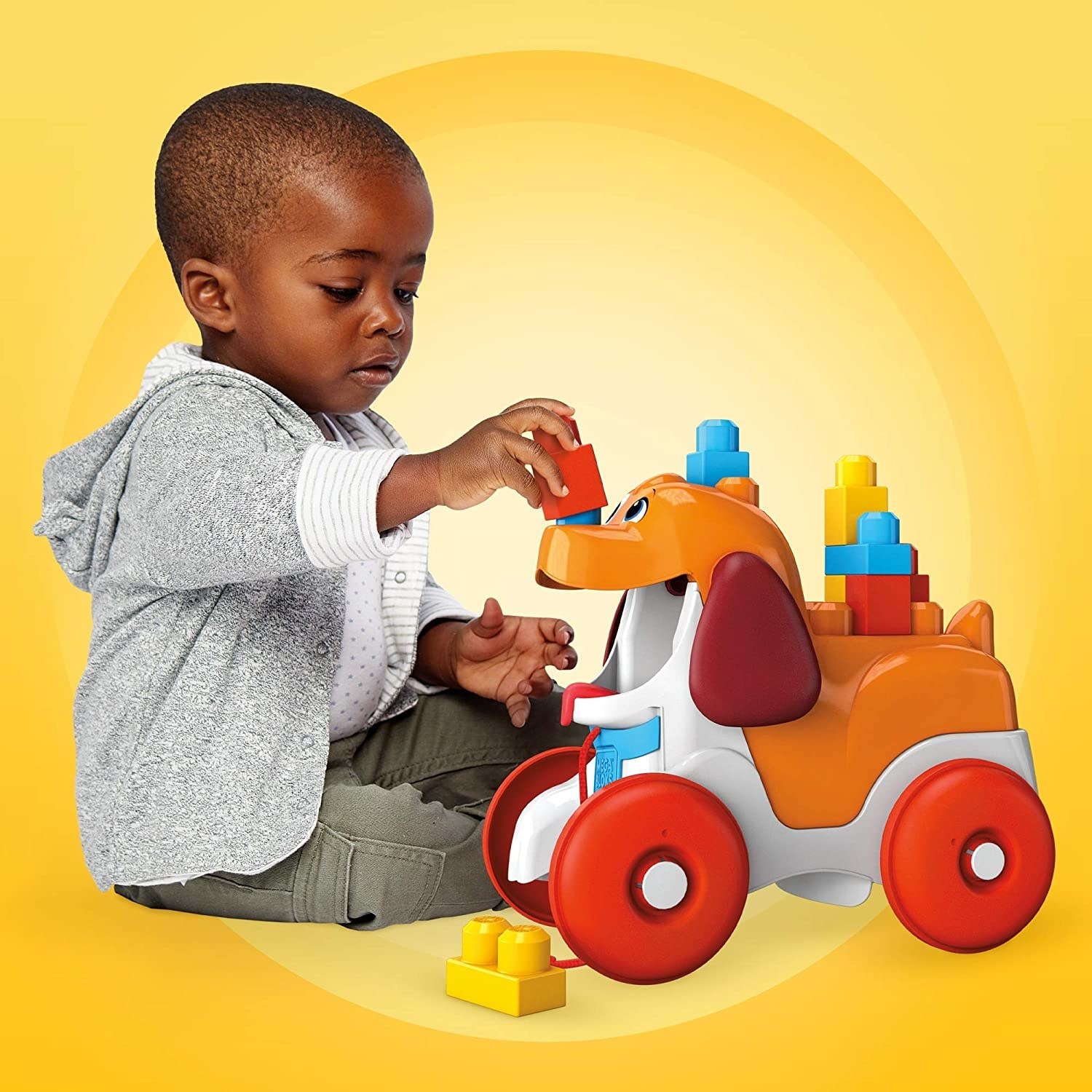 Child model playing with bright plastic dog toy with red wheels