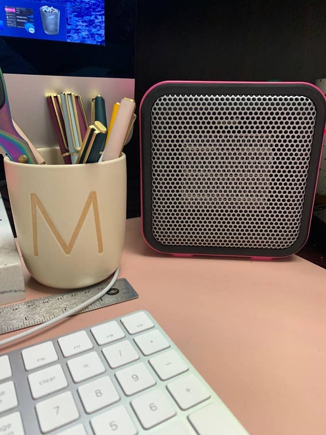 The small, pink, square heater on a reviewer's desk; it's about the height of the pens in a mug and has a protective metal grating with holes on the front