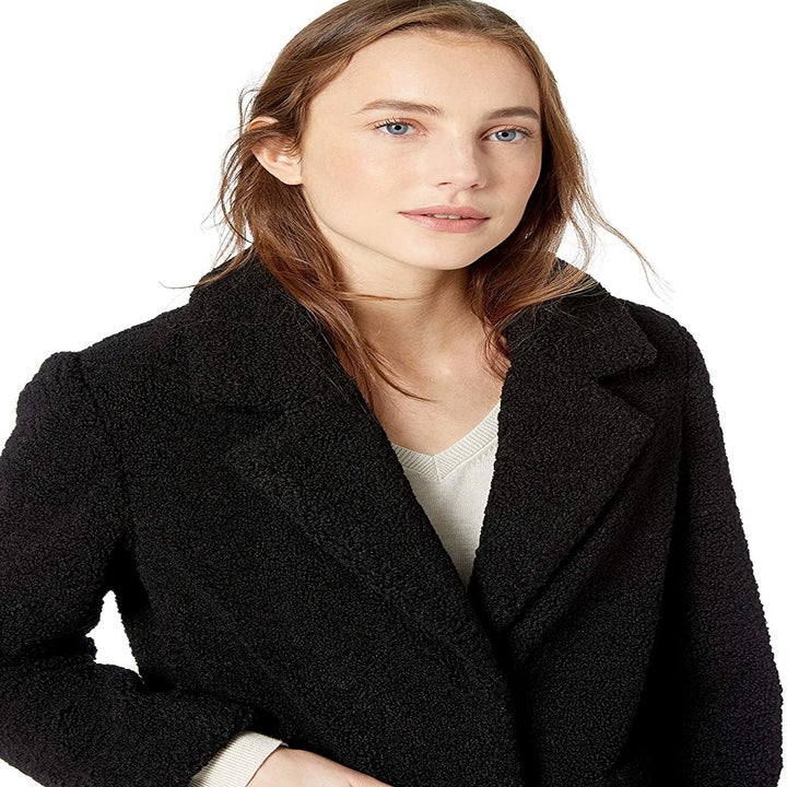 Model wearing jacket in black, showing collar and raised sleeve at seam 