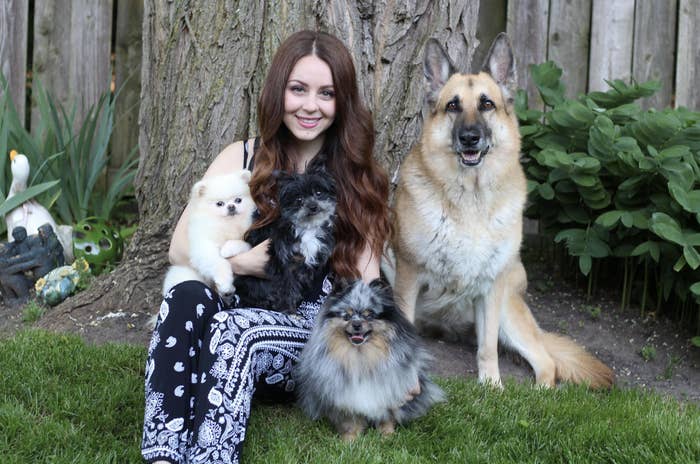 Vanessa sitting in front of a tree with four dogs