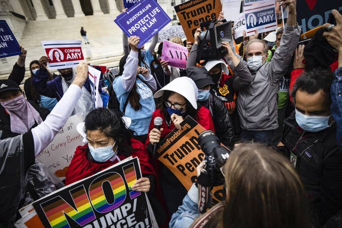 Several people stand outside the Supreme Court holding signs for and against Amy Coney Barrett