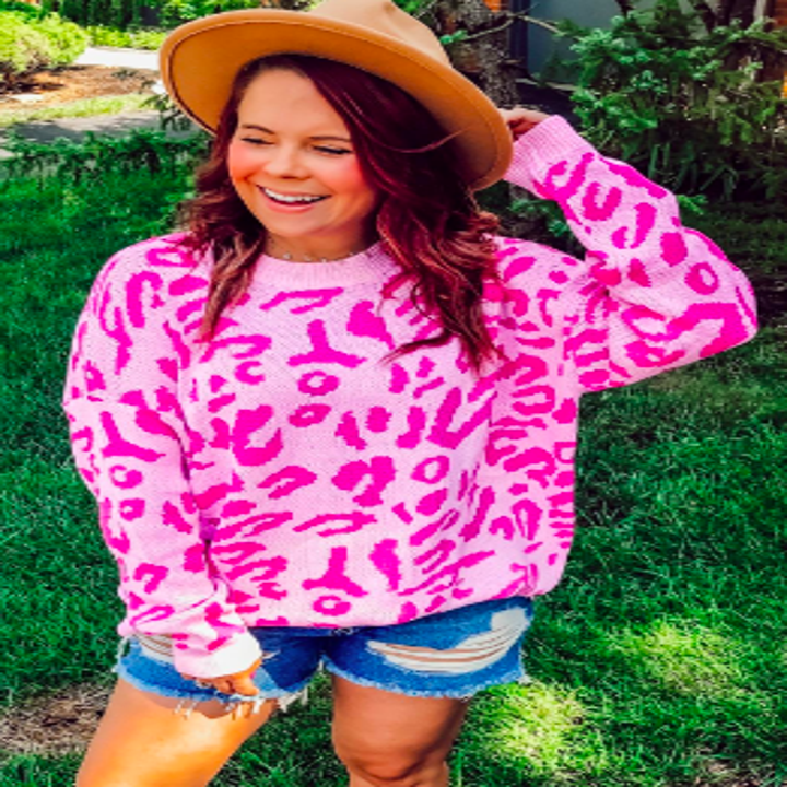 Reviewer wearing oversized sweater in hot pink leopard print with shorts