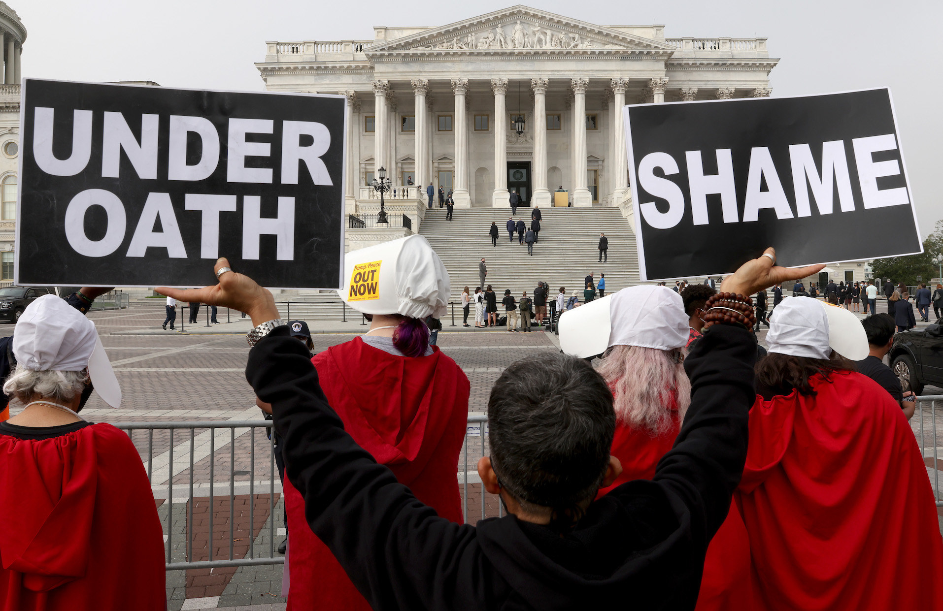 Several people wearing costumes from the television show The Handmaid&#x27;s Tale standing outside The Supreme Court