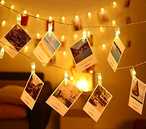 Tiny photo notecards hanging on lit string lights with slim clips