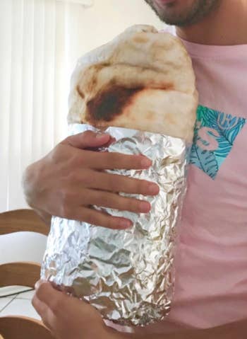 Reviewer holds burrito blanket wrapped up in real foil after receiving it as a gift