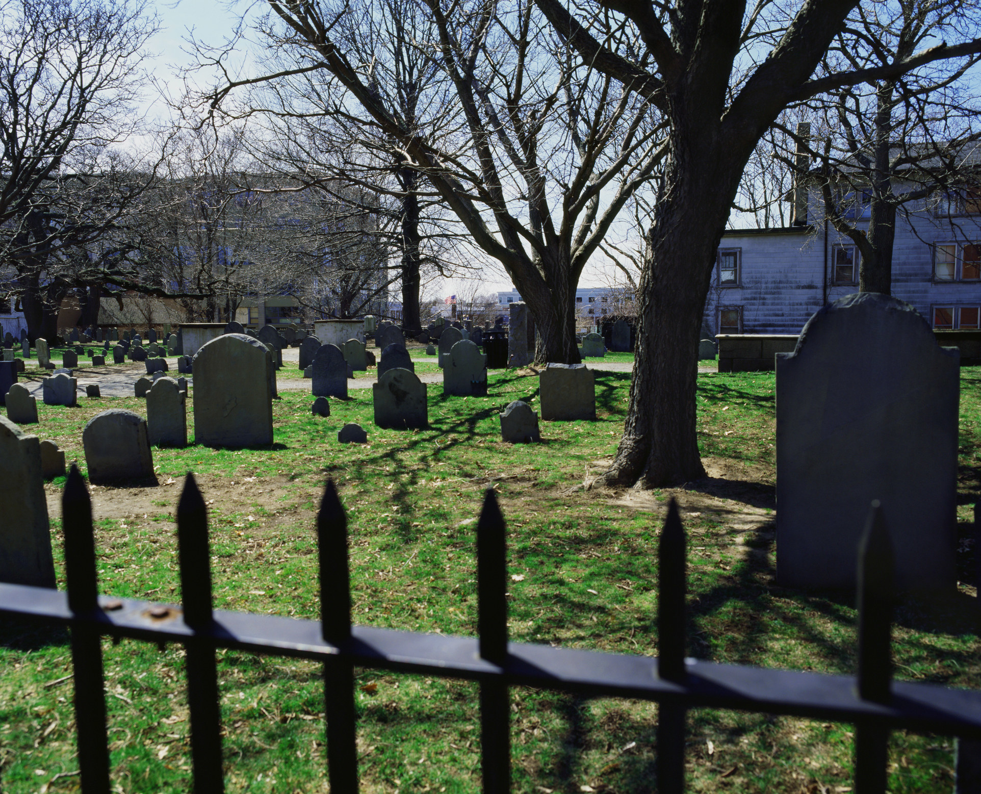 a fenced off grassy field with gravestones and trees