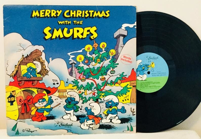 The cover Merry Christmas with the Smurfs album which features Papa Smurf leading a chorus of three singing Smurfs and Smurfette looking from the window