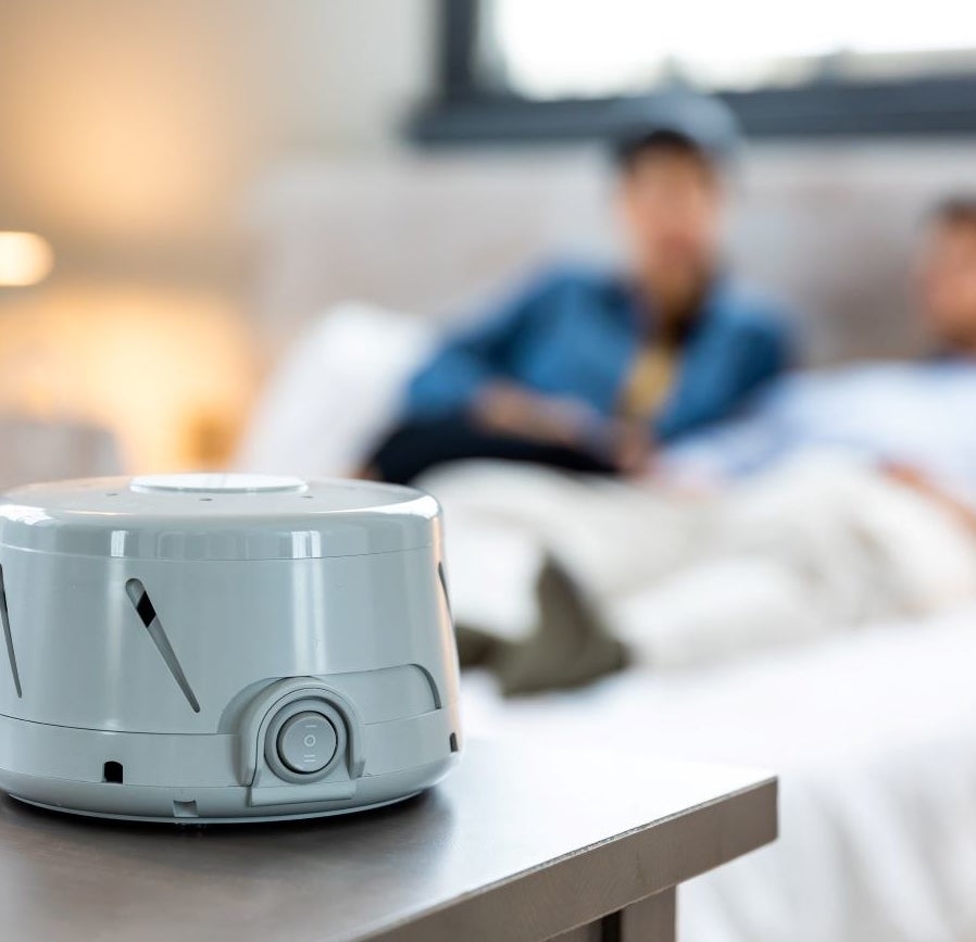 gray white noise machine sitting on a dresser in a bedroom
