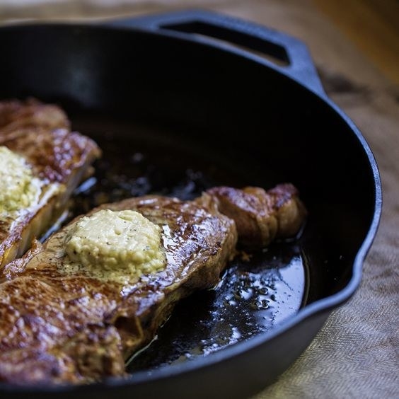 a steak being cooked in a cast iron skillet