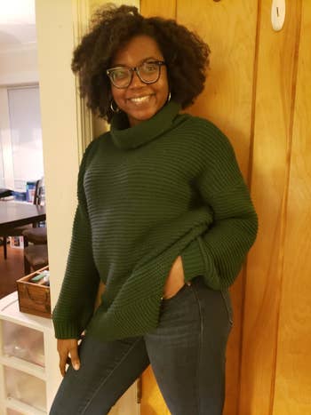 A customer review photo of them wearing the sweater in dark green