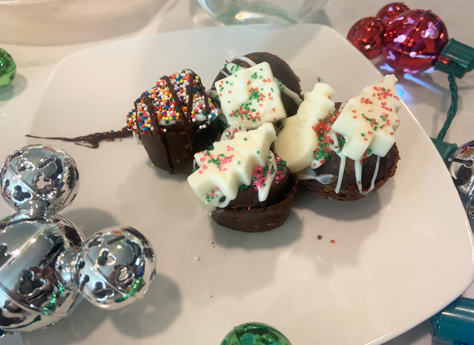 the finished cocoa bombs have sprinkles, drizzled chocolate, and little white chocolate embeds