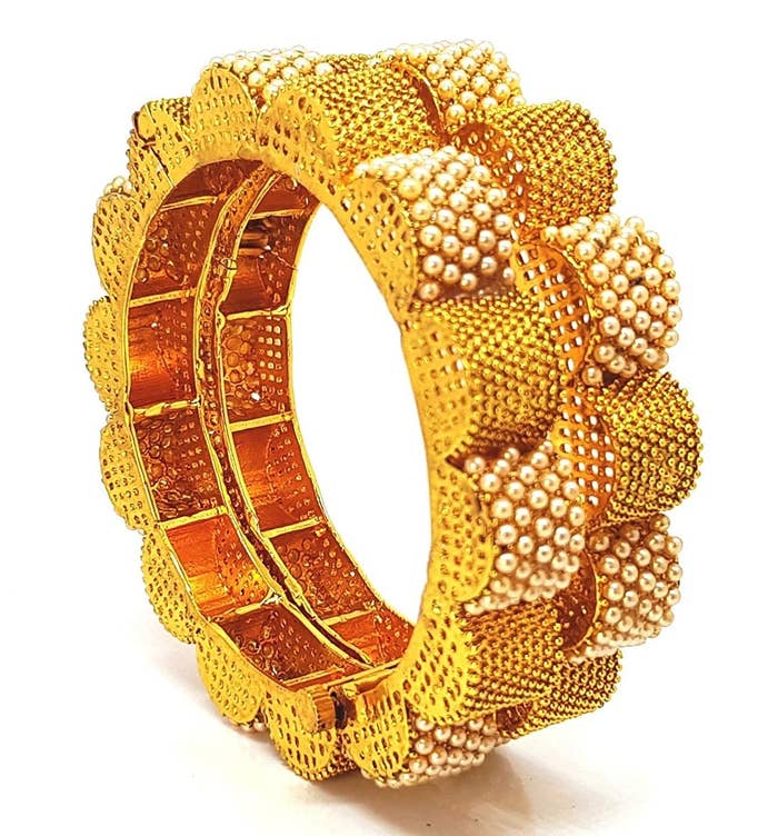 Two pairs of golden bangles with raised semic-circles, studded with pearls on the outside.