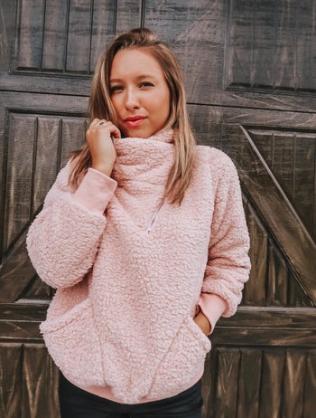 Reviewer wearing the jacket in pink with turtleneck-style top neckline and two large pockets at the bottom
